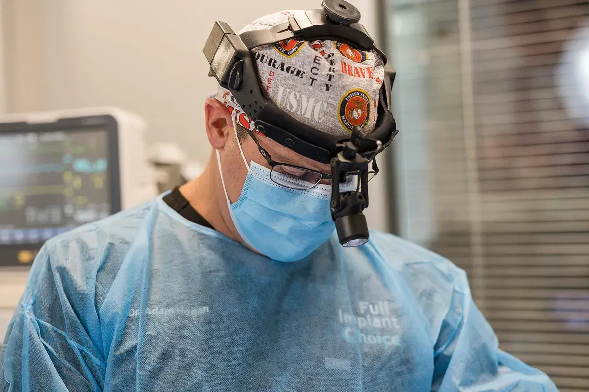 Dr. Hogan in surgical loupes performing a full-arch dental implant procedure